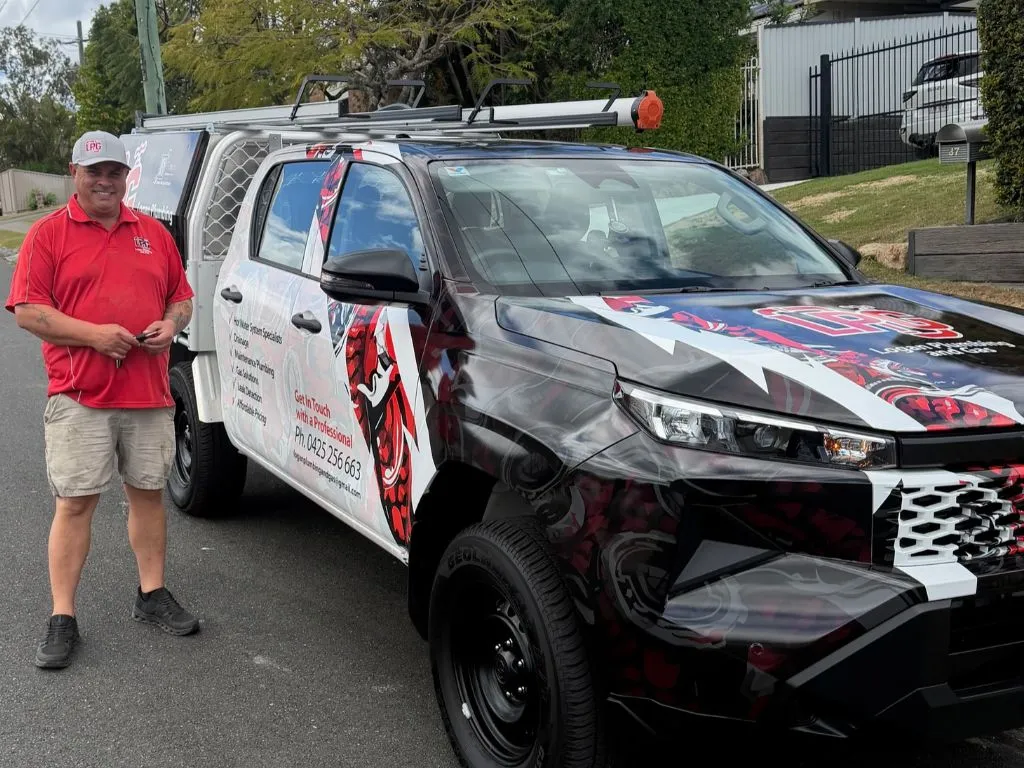 Logan Plumbing & Gas plumber standing beside the company ute