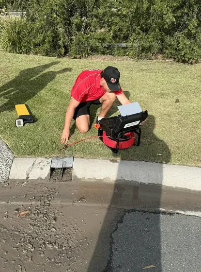 Plumber using drain clearing equipment in a Logan backyard