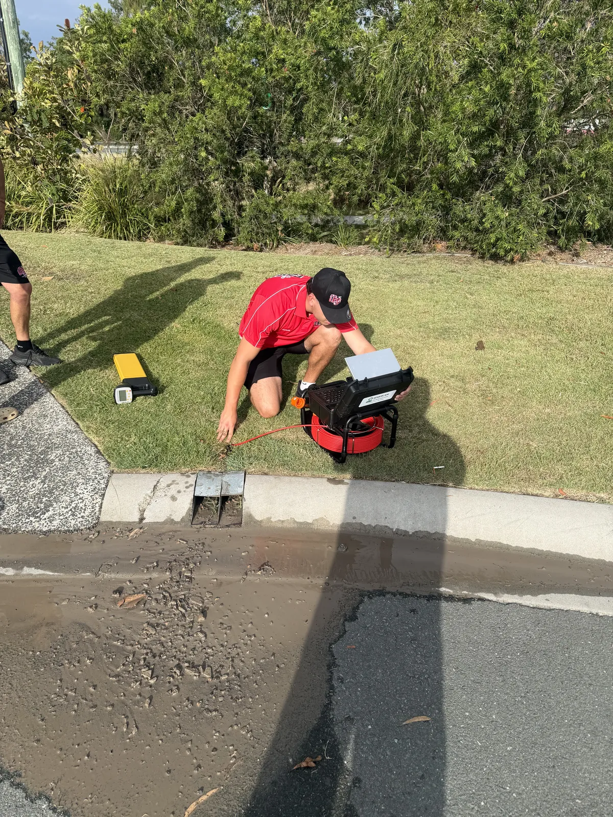 Plumber using a CCTV drain camera at a kerb outlet in Logan Reserve