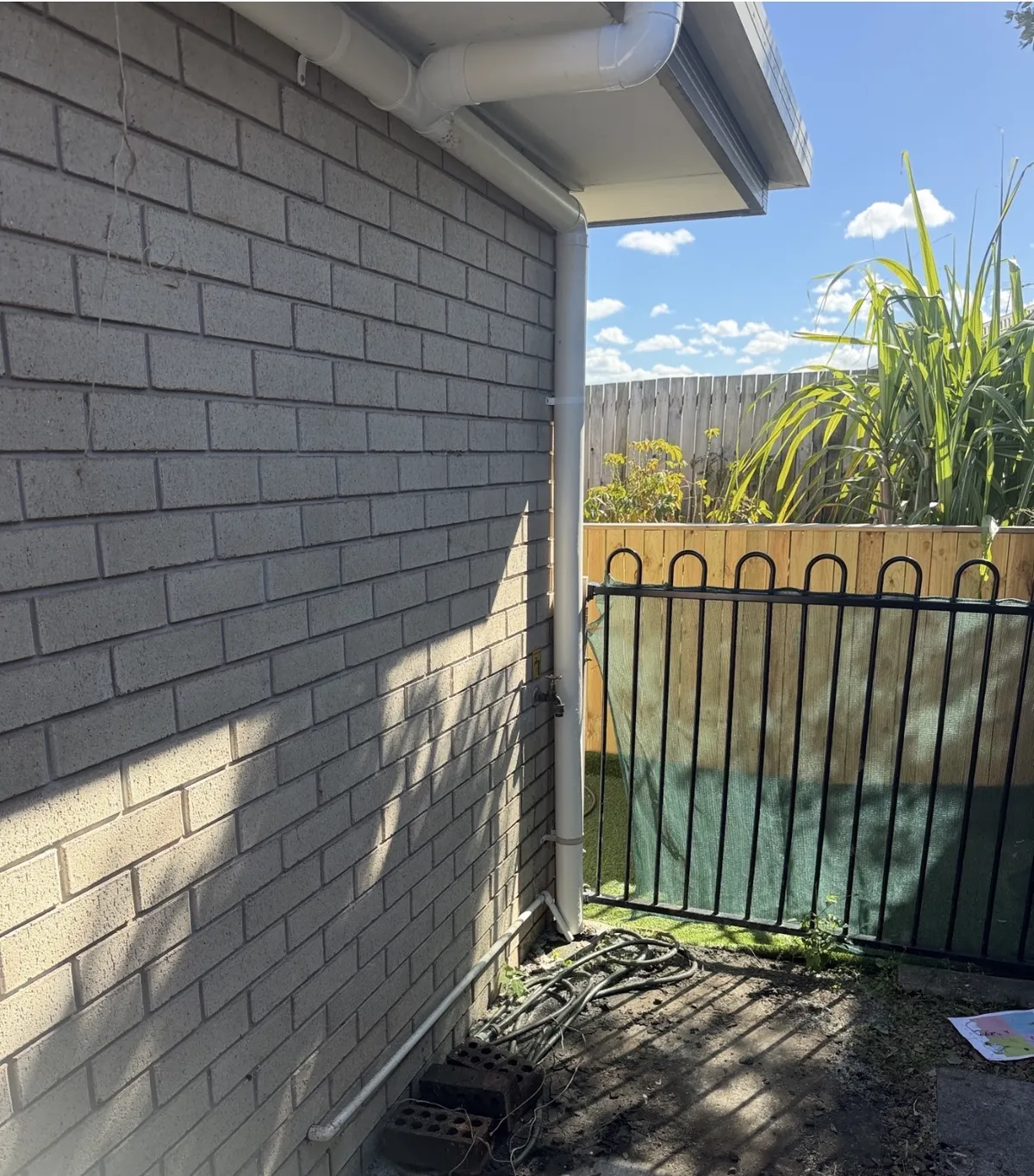 Before and after photos of a downpipe connection into a stormwater drain